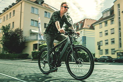 Je ziet een man op een Winora-fiets door het stadscentrum rijden.