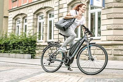 Een vrouw rijdt door het stadscentrum met een handtas onder haar arm op een Winora fiets.