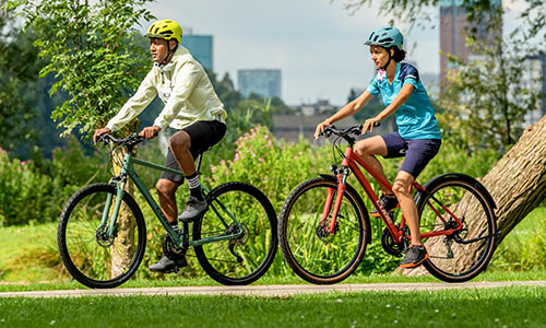 Fietser en wielrenner rijden op crossfietsen langs een park.