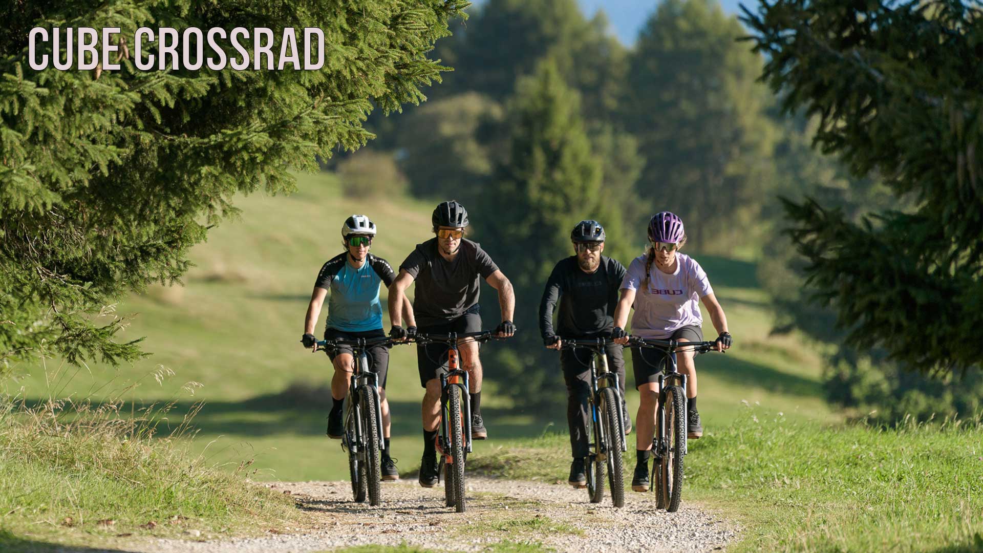 De foto laat een groep fietsers zien die over een bospad rijdt. De foto is gelabeld met de titel Cube Crossrad.