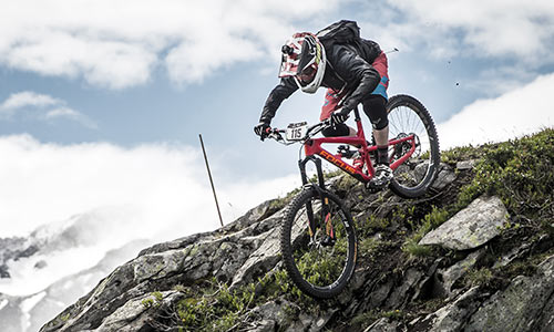 Downhill fietser met integraalhelm die over rotsen een rotsachtige berg afrijdt.
