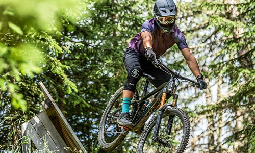 Een fietser met een integraalhelm op rijdt door het bos op een mountainbike.